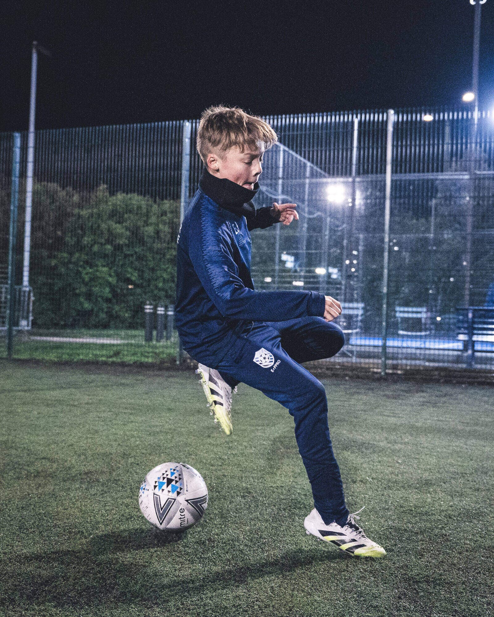 An E-PPRO player controlling the ball during a floodlit night training session